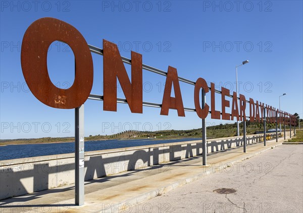 Large red rusty capital letters ON A CLEAR DAY YOU CAN SEE FOREVER blue sky background, Alqueva dam, Moura, Portugal, Europe
