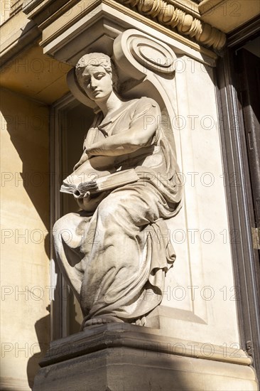 Victorian sculpture of woman reading a book outside old library building in city centre, Cardiff, South Wales, UK