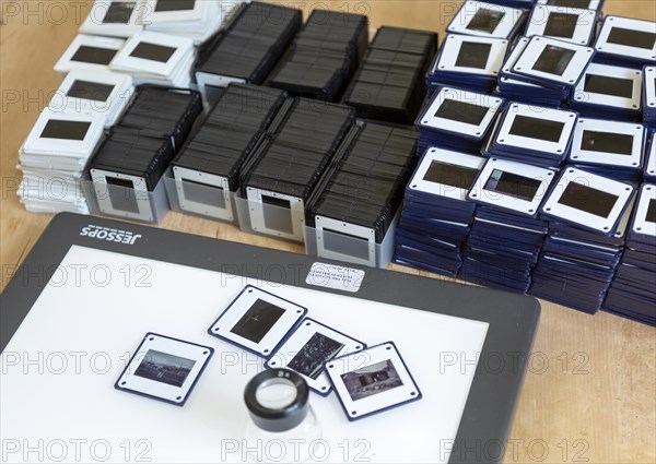 Piles of film transparency slides and Lightbox with viewing enlarger loupe