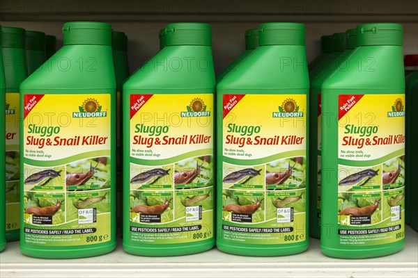 Plastic containers of Neudorff Sluggo slug and snail killer on shelf display in garden centre, UK