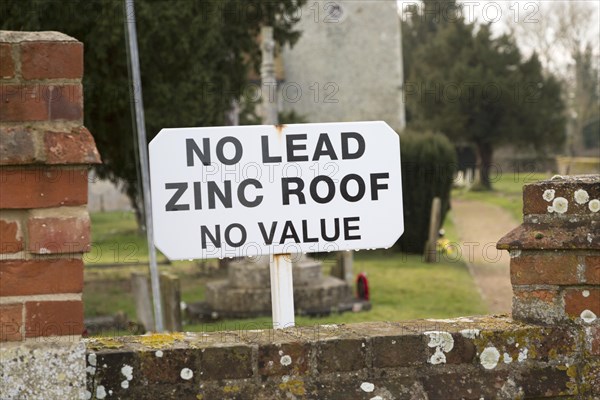 No Lead Zinc Roof No Value sign outside church to deter potential thieves who target churches for their lead roofs, Ellingham, Norfolk, England, UK