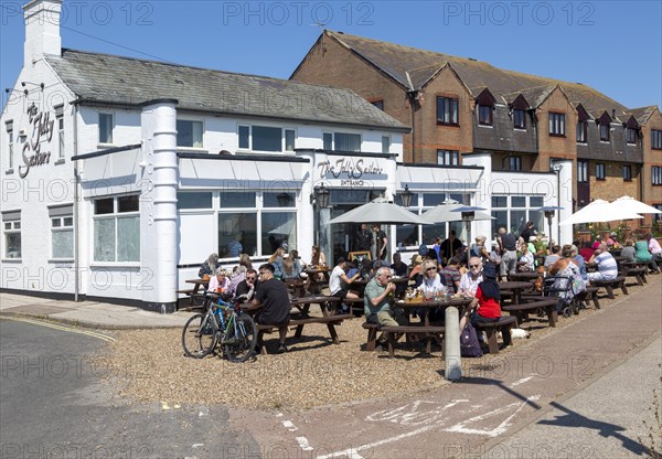 People sitting in sunshine outside the Jolly Sailors pub, Pakefield, Lowestoft, Suffolk, England, UK