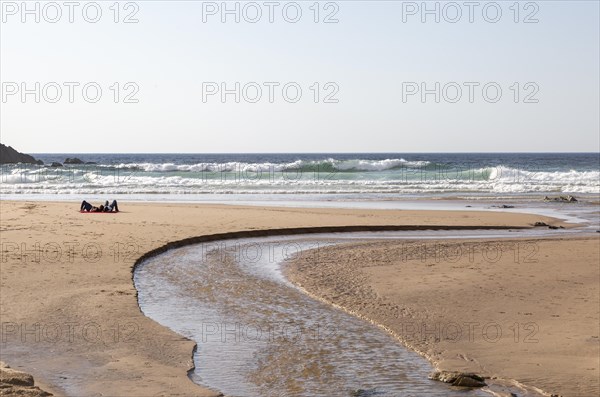 Two people lying by sea on sandy Praia Carvalhal beach, Brejao, Alentejo Littoral, Portugal, Southern Europe, Europe