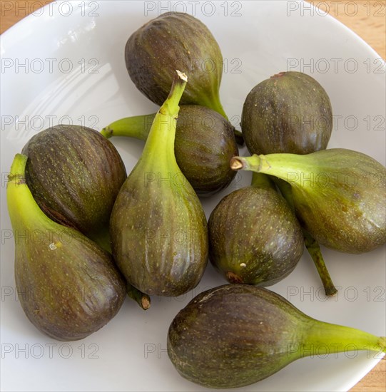 White fruit bowl of figs from above oblique angle close up