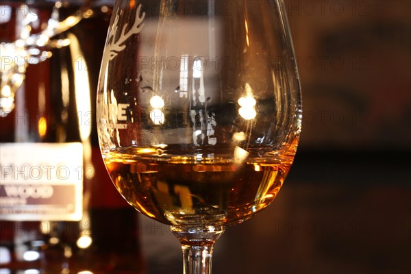 Close-up of a glass of whiskey with a bottle of Dalmore single malt in the background