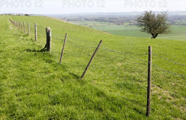 Fence running along top of chalk scarp slope looking south east over Vale of Pewsey, near Knap Hill, Wiltshire, England, Uk