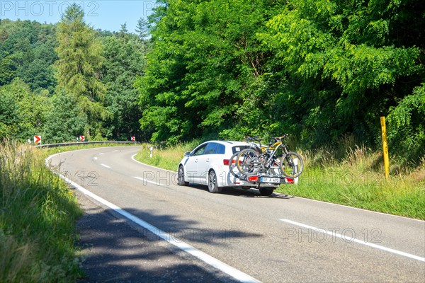 White car with Thule rear bike rack on a country road in Dahner Felsenland Germany