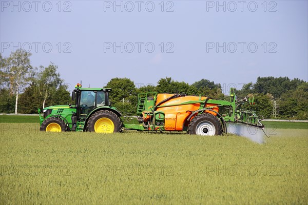 A farmer drives his tractor with a crop protection sprayer across his wheat field to combat brown rust and mildew (Hockenheim, Baden-Wuerttemberg)