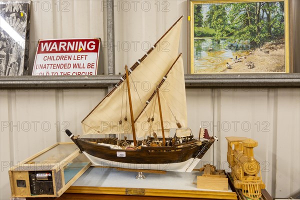 Model sailing ship and other items on display inside an auction room