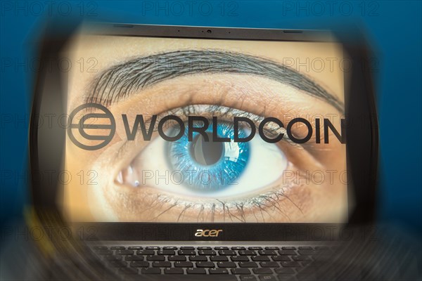 Logo of the new cryptocurrency Worldcoin on a laptop. Anyone wishing to participate in World Coin must register with their biometric data (symbolic image)