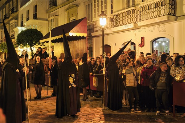 Nazarenos with black robes and typical pointed bonnets, insignia, Semana Santa, procession, night shot, celebrations in Tarifa, Spain, Europe