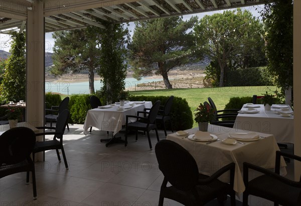 Outdoor dining terrace tables and chairs, Hotel La Vinuela, Axarquia, Andalusia, Spain with view of garden and lake