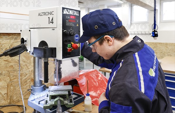 A trainee mechatronics technician works with a bench drill on a workpiece in a Deutsche Bahn training centre, Berlin, 07/02/2024
