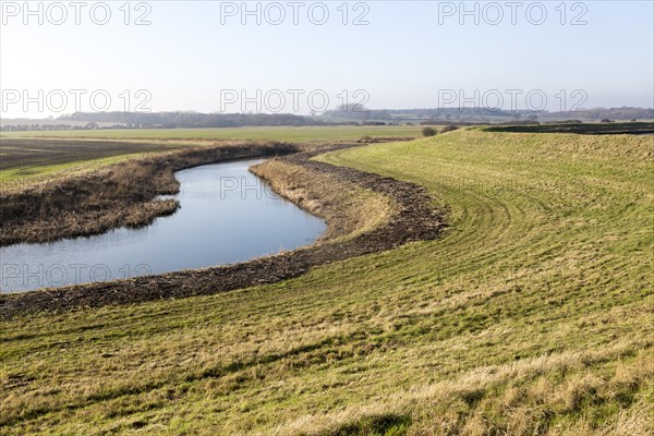 Drainage channel lowland fields inland from flood defence dyke wall, River Deben valley, Falkenham, Suffolk, England, UK