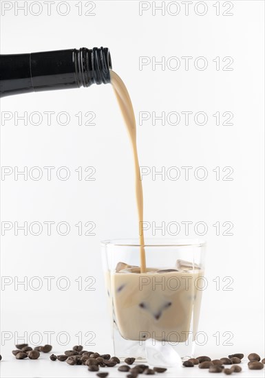 Baileys is poured into a glass with ice and coffee beans, movement is visible