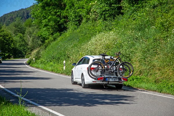 White car with Thule rear bike rack on a country road in Dahner Felsenland Germany