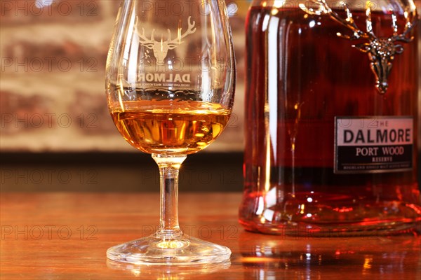 Close-up of a glass of whiskey with a bottle of Dalmore single malt in the background