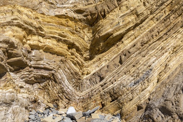 Strata of sandstone sedimentary rock in a coastal cliff with layers folded down to form a geological structure called a syncline, near Zambujeiro do Mar, Alentejo Littoral, Portugal, southern Europe. A syncline is a trough or fold of stratified rock in which the strata slope upwards from the axis. Folds typically form during crustal deformation as the result of compression that accompanies orogenic mountain building, Europe