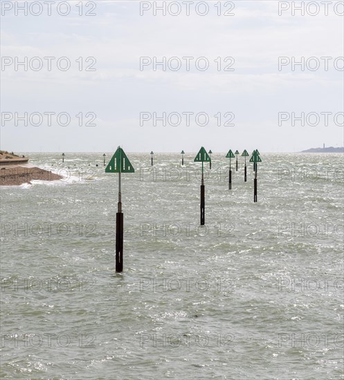 Green triangular warning markers on posts in shallow water at River Orwell river mouth, Landguard Point, Felixstowe, Suffolk, England, UK
