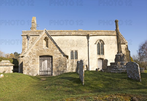 Building exterior historic church of Saint John, Inglesham, Wiltshire, England, UK 13th century building with 15th century churchyard cross