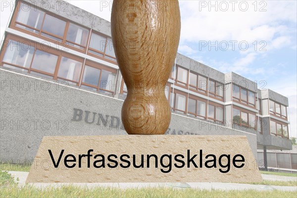 Symbolic image of a constitutional complaint: in the foreground a stamp, in the background the Federal Constitutional Court in Karlsruhe