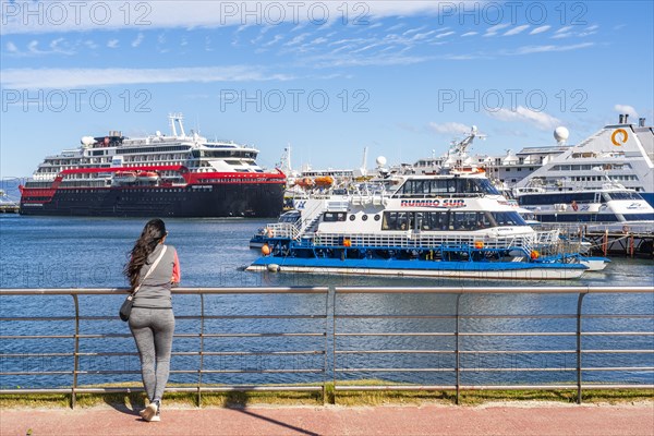 A woman watches cruise ships in the harbour on the Beagle Channel, Ushuaia, Tierra del Fuego Island, Patagonia, Argentina, South America