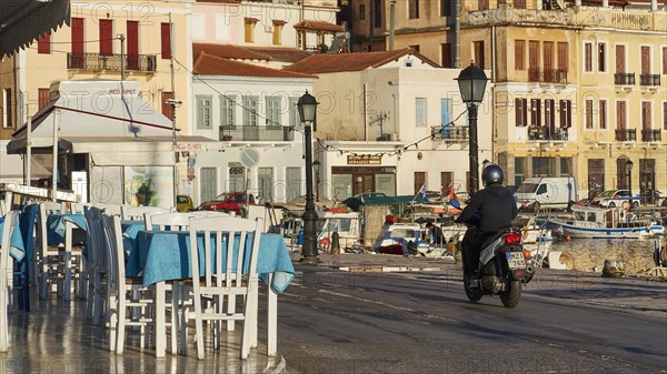 A scooter rides early in the morning at a cafe along the coastal road overlooking the sea, Gythio, Mani, Peloponnese, Greece, Europe