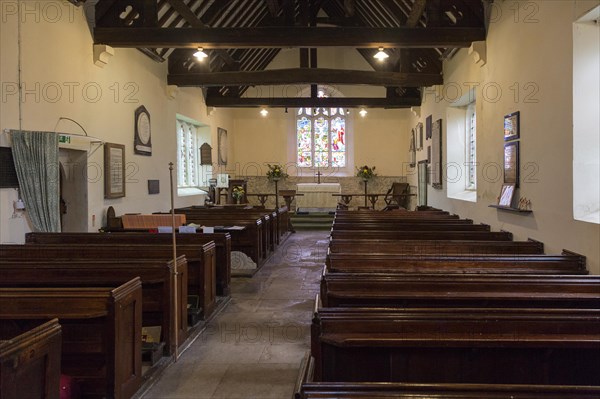 Wooden pews, altar, and east window with undivided nave and sanctuary inside the church at Easton Royal, Wiltshire, England built in 1591