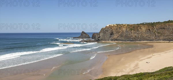 Coastline view of headlands and bay with wide sandy beach, surfer and a few sunbathers, Praia de Odeceixe, Algarve, Portugal, Southern Europe, Europe