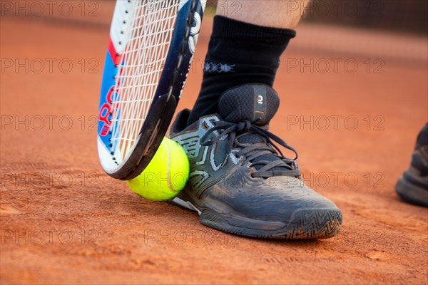 Tennis symbol: Close-up of a tennis player on a clay court wearing black ON tennis shoes
