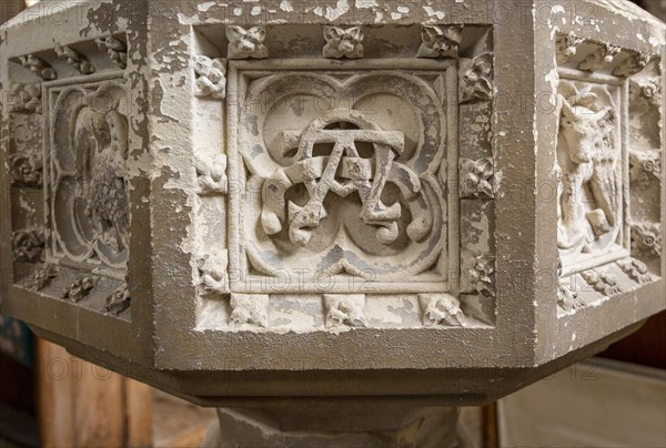 Historic interior of East Bergholt church, Suffolk, England, UK baptismal font stonework detail alpha omega symbol