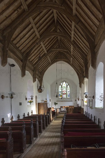Looking east down the nave towards the altar and east window with historic wooden carved pews, fine wooden roof, whitewashed walls, interior of small village parish church at South Cove, Suffolk, England, UK