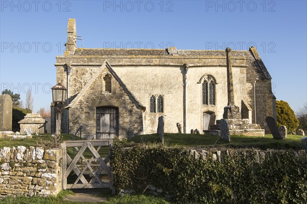 Building exterior historic church of Saint John, Inglesham, Wiltshire, England, UK 13th century building with 15th century churchyard cross