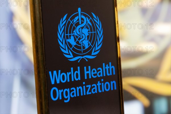 Symbolic image: Smartphone with WHO (World Health Organisation) logo against a blurred background