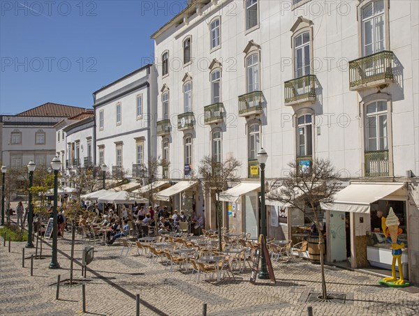 People sitting in sunshine outside street cafes in Praca da Republica, Tavira, Algarve, Portugal, Southern Europe, Europe
