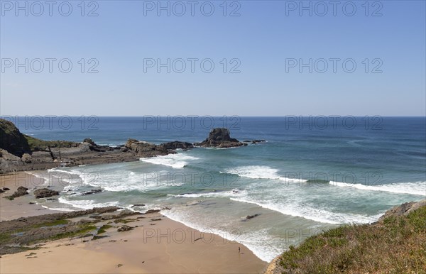 Sandy Carvalhal beach in bay between rocky headlands at Parque Natural do Sudoeste Alentejano e Costa Vicentina, Costa Vicentina natural park, near Brejao, south west Alentejo, Alentejo Littoral, Portugal, Southern Europe. One small figure of a person is visible standing on the shoreline, Europe