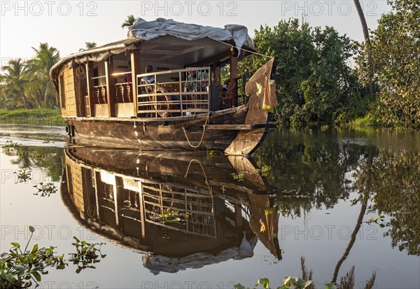 A traditional houseboat cruises along the channels near Kumarakom, offering a glimpse into the unique way of exploring the tranquil Kerala backwaters, India, Asia