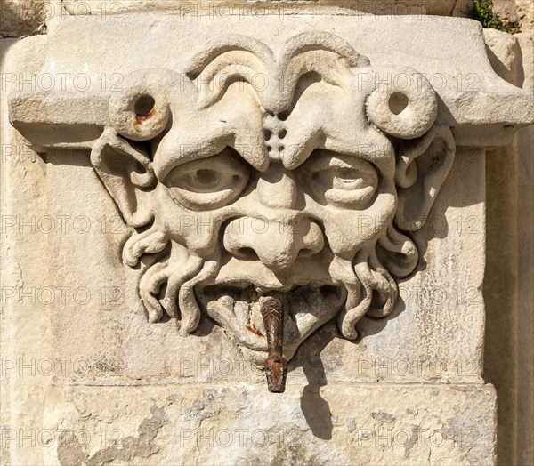 Carved stone face on old fountain in Cuenca, Castille La Mancha, Spain snake spout emerging from mouth