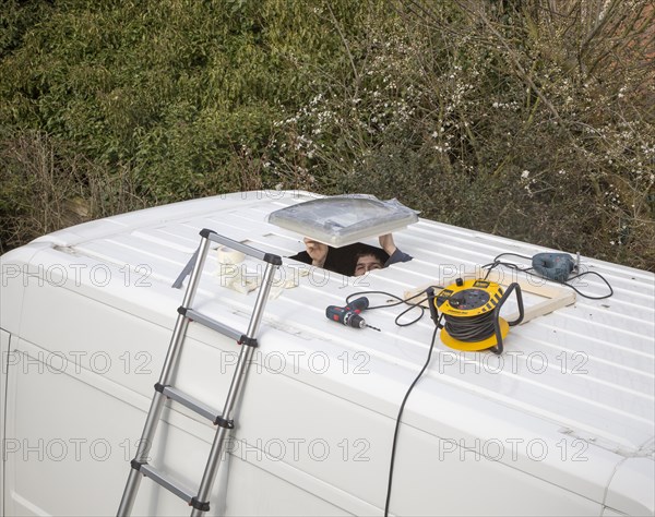 Cutting through roof of white metal camper van conversion to install ventilation window, UK