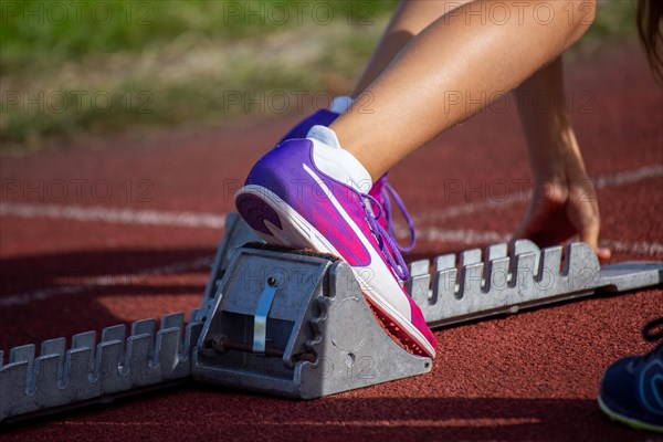 Young track and field athlete with Cougar spikes at the starting block in front of a sprint