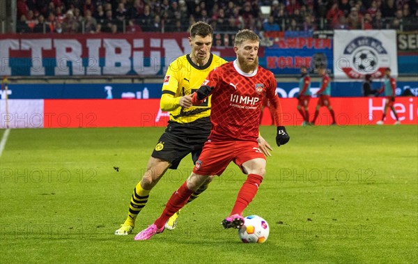 Football match, captain Patrick MAINKA 1.FC Heidenheim is pressurised by l.t.r. Nico SCHLOTTERBECK Borussia Dortmund, Niclas FUeLLKRUG Borussia Dortmund and Donyell MALEN Borussia Dortmund during a header, football stadium Voith-Arena, Heidenheim