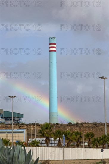 Rainbow in stormy sky behind tall blue industrial cement factory chimney, Carboneras, Almeria, Spain, Europe
