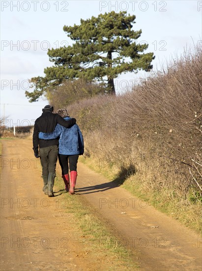 Young couple man woman winter country walk from behind, Suffolk, England, UK