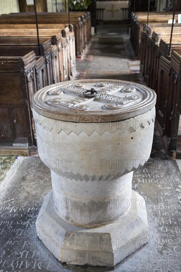 Simply decorated stone 12th century baptismal font inside church at Stanton St Bernard, Wiltshire, England, UK