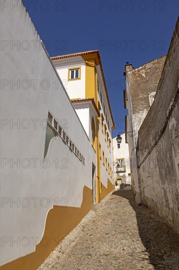 Residential buildings in cobbled alley with historic whitewashed houses. An image of life one of the old neighbourhoods in the city centre of Evora, Alto Alentejo, Portugal, southern Europe, Europe
