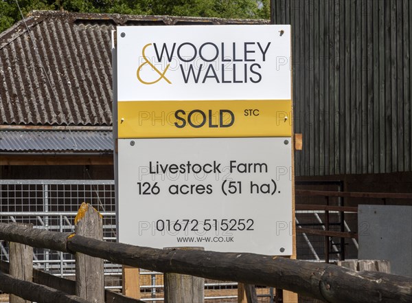 Estate agent Woolley and Wallis property sold sign at livestock farm near Potterne, Wiltshire, England, UK