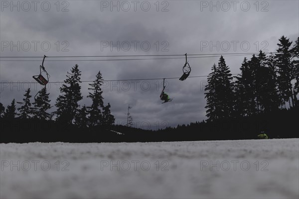 Skiers ride a chairlift, taken on a ski slope in the Jizera Mountains ski area near Albrechtice v Jizerskych Horach, 05.02.2024. The Czech low mountain range with its ski area is affected by increasingly warmer and shorter winters