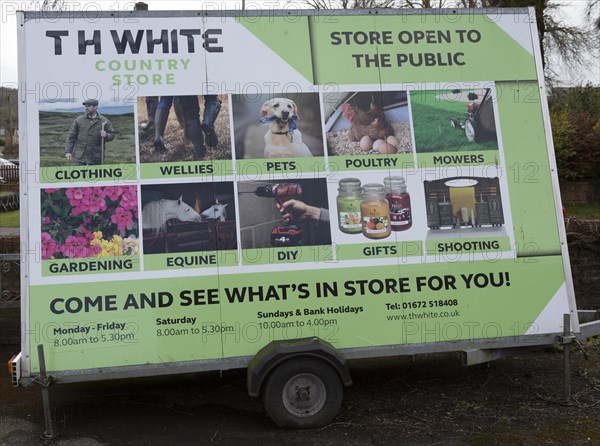 Mobile wheeled advertising hoarding for TH White country store shop, Marlborough, Wiltshire, England, UK