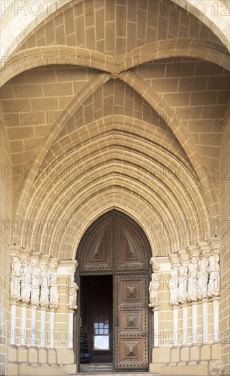 Historic Roman Catholic cathedral church of Evora, Se de Evora, in the city centre, Basilica Cathedral of Our Lady of Assumption. This image shows details of the carved Gothic period main doorway entrance with carved Apostles either side of the door. The arched ogive or ogival arch is considered a masterpiece of Portuguese Gothic art