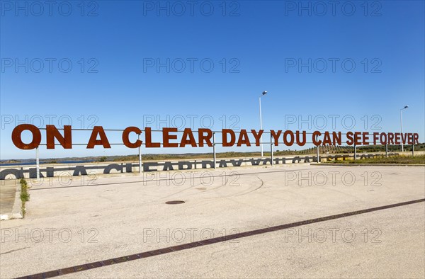 Large red rusty capital letters ON A CLEAR DAY YOU CAN SEE FOREVER blue sky background, Alqueva dam, Moura, Portugal, Europe